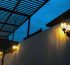 Vintage outdoor wall light illuminating a building exterior under a dark sky.