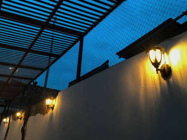 Vintage outdoor wall light illuminating a building exterior under a dark sky.