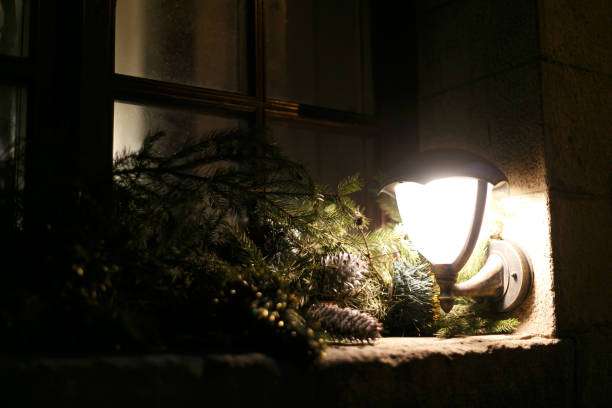 Rustic outdoor Wall Light illuminating festive pine branches and pinecones at night.