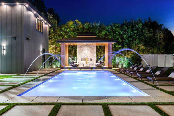 Elegant home with illuminated pool, gazebo, and stylish Wall Light fixtures at dusk.