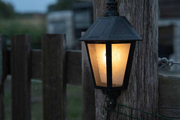 Illuminated outdoor solar light lantern on a wooden post, providing warm evening light.