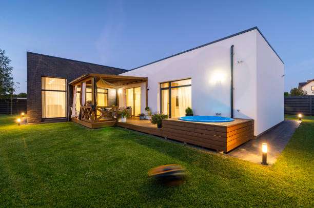 Modern house with a spacious lawn, deck, hot tub, and warm Wall Light.