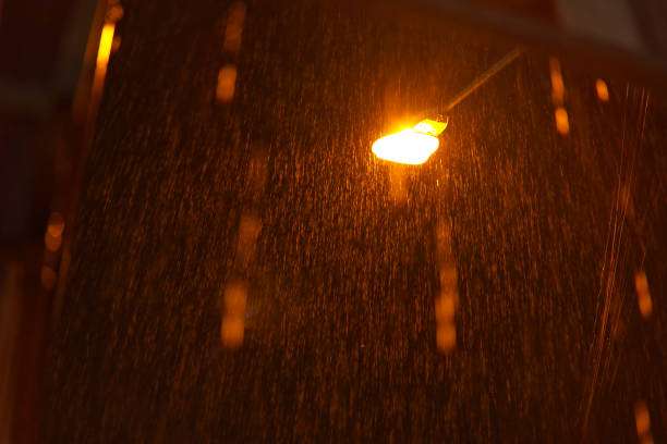 Bright outdoor solar light shining through heavy rain, illuminating a dark, stormy night.